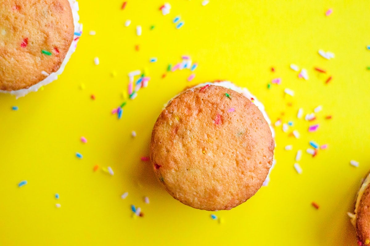 Cake mix whoopie pies and ice cream sandwiches with colorful sprinkles on a bright yellow background.