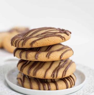 A stack of chocolate dipped peanut butter cookies on a plate.