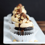 A white plate with snickers cupcakes on it.