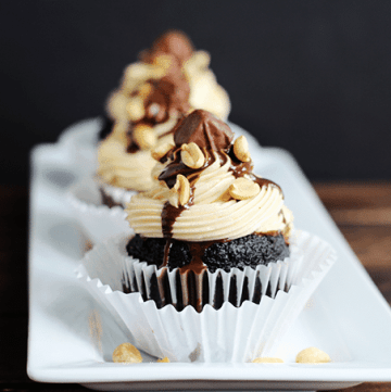 A white plate with snickers cupcakes on it.