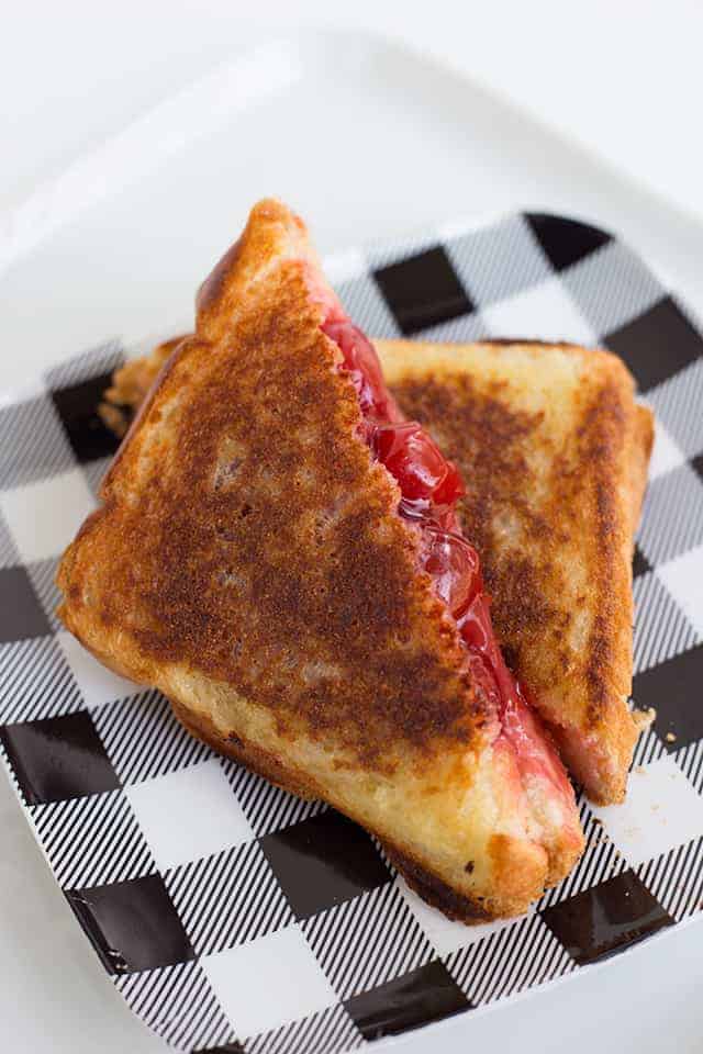 Cherry mountain pie cut in half on a black and white plaid plate