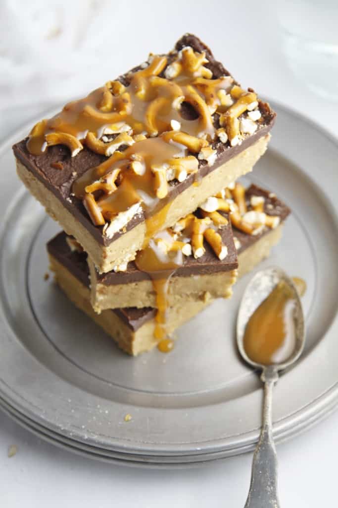 No Bake peanut butter pretzel bars stacked on a plate with caramel dripping