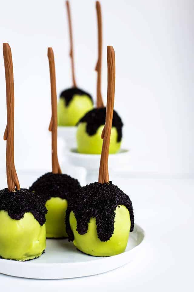 three Poison apple cake pops on a white plate