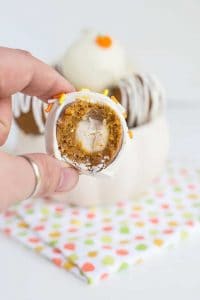 a bite taken out of the pumpkin white chocolate cake pops with other cake pops behind it
