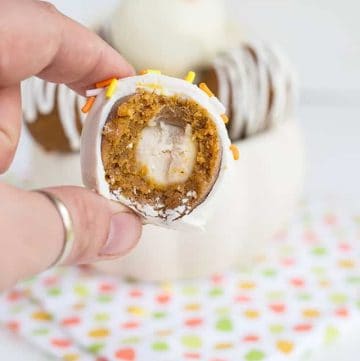 a bite taken out of the pumpkin white chocolate cake pops with other cake pops behind it