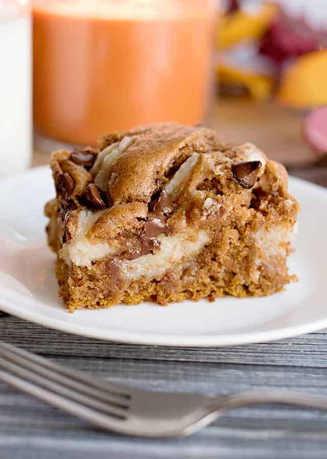 Pumpkin cheesecake bars on a white plate with a hint of the Pumpkin Earthquake Cake.