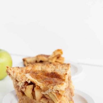 a slice of apple pie with cheddar cheese crust on a white plate