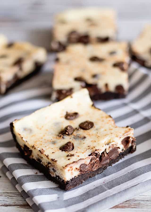 close up of eggnog cheesecake bars on a gray striped linen