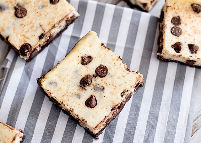 eggnog cheesecake bars with chocolate chips on a gray and white fabric