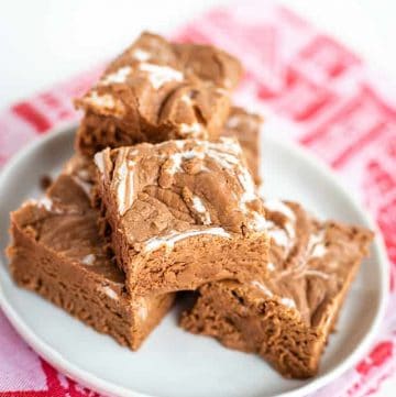 chocolate marshmallow fudge piled on a white plate with red hand towel