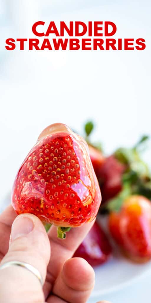 A person holding a candied strawberry.