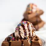 chocolate waffles stacked with whipped cream and chocolate syrup