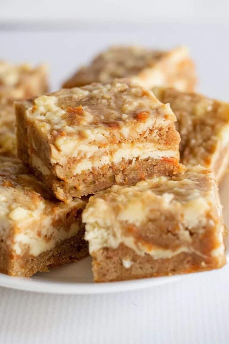 A stack of carrot cake bars layered with cheesecake.