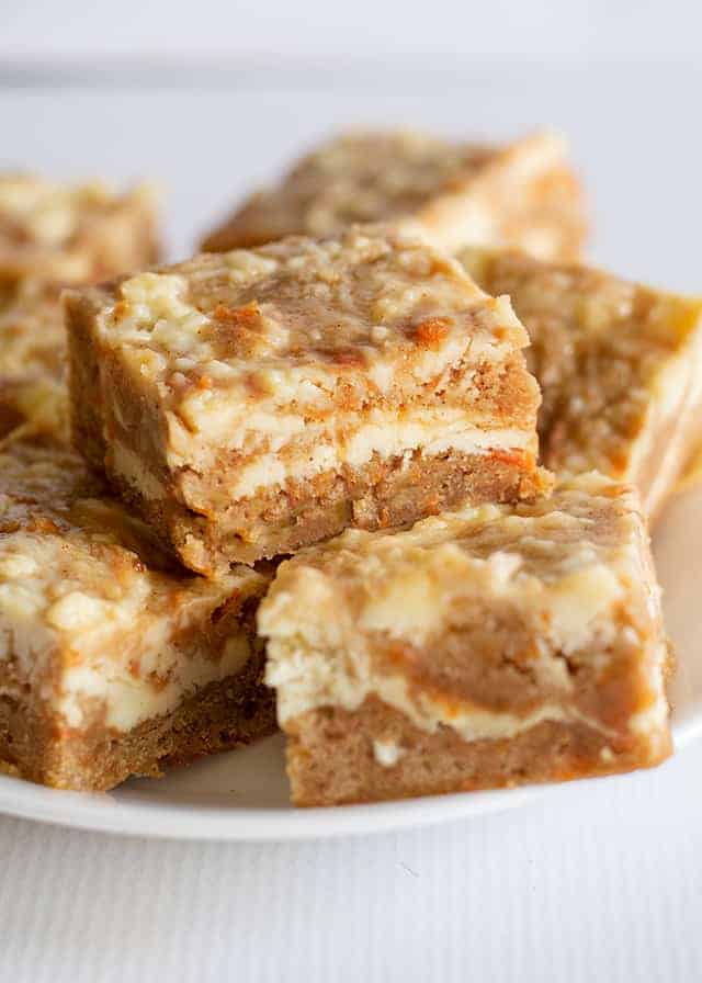 Carrot Cake Bars - These carrot cake bars are so moist and delicious! They have a sprinkle of cinnamon and a cheesecake swirl in them. They're the perfect Easter dessert bars. #easterrecipes #easter #bars #desserts #dessertfoodrecipes #dessertrecipes #desserttable #dessertideas #cookiedoughandovenmitt carrot cake bars stacked