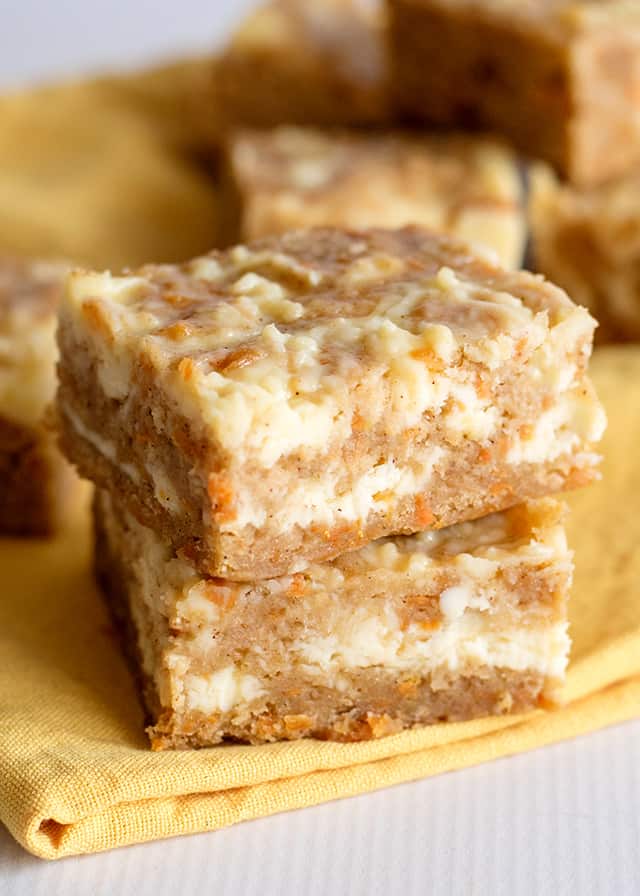 two carrot cake bars stacked on yellow linen