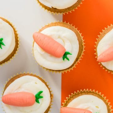 close up carrot cake cupcakes on a white and orange background