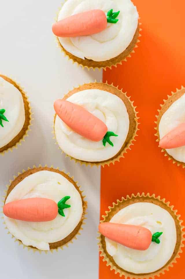 close up carrot cake cupcakes on a white and orange background
