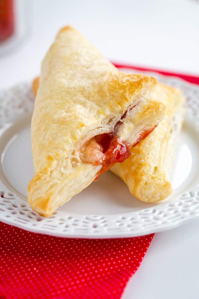 Strawberry Cream Cheese Turnovers - This easy strawberry cream cheese turnover recipe is flaky and delicious. Each turnover is stuffed with cream cheese and strawberry jam. They're brushed with an egg wash to give them a golden shell. #cookiedoughandovenmitt #breakfastrecipes #breakfast #strawberries #tunovers