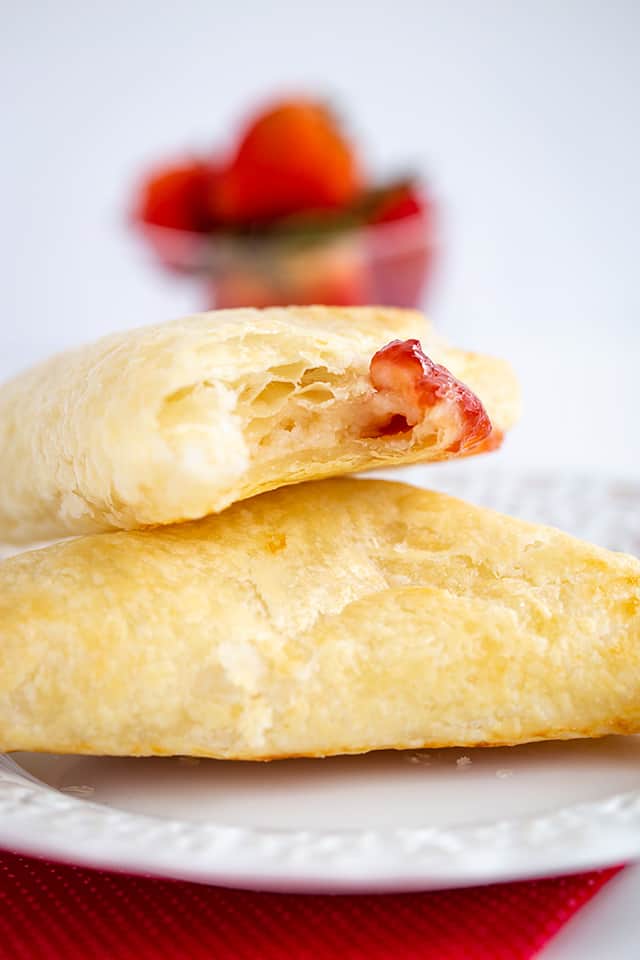Strawberry Cream Cheese Turnovers - This easy strawberry cream cheese turnover recipe is flaky and delicious. Each turnover is stuffed with cream cheese and strawberry jam. They're brushed with an egg wash to give them a golden shell. #cookiedoughandovenmitt #breakfastrecipes #breakfast #strawberries #tunovers