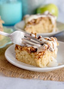 fork full of apple fritter cake on white plate