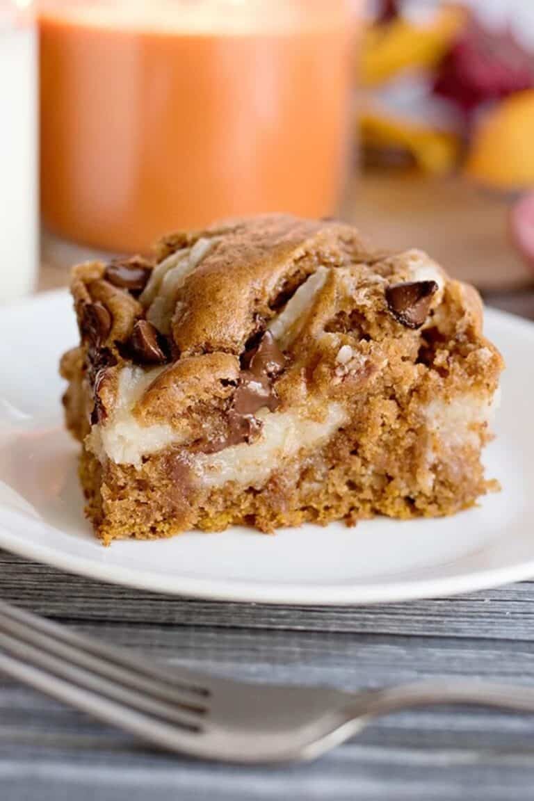 A square slice of pumpkin earthquake cake with a cream cheese swirl on a white plate.