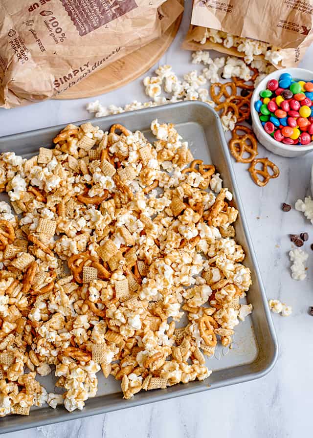 Caramel Chex Mix - Caramel Chex Mix is the perfect mix of salty and sweet to curb your snack cravings. This caramel check mix recipe is loaded with pretzel twists, sweet caramel flavor, Chex, popcorn, and more. It's made with a homemade caramel sauce and is baked in the oven. If you love snack mixes, give this sweet chex mix recipe a try! #cookiedoughandovenmitt #snackrecipe #caramel #snacks #fallrecipes sheet pan with caramel chex mix in it