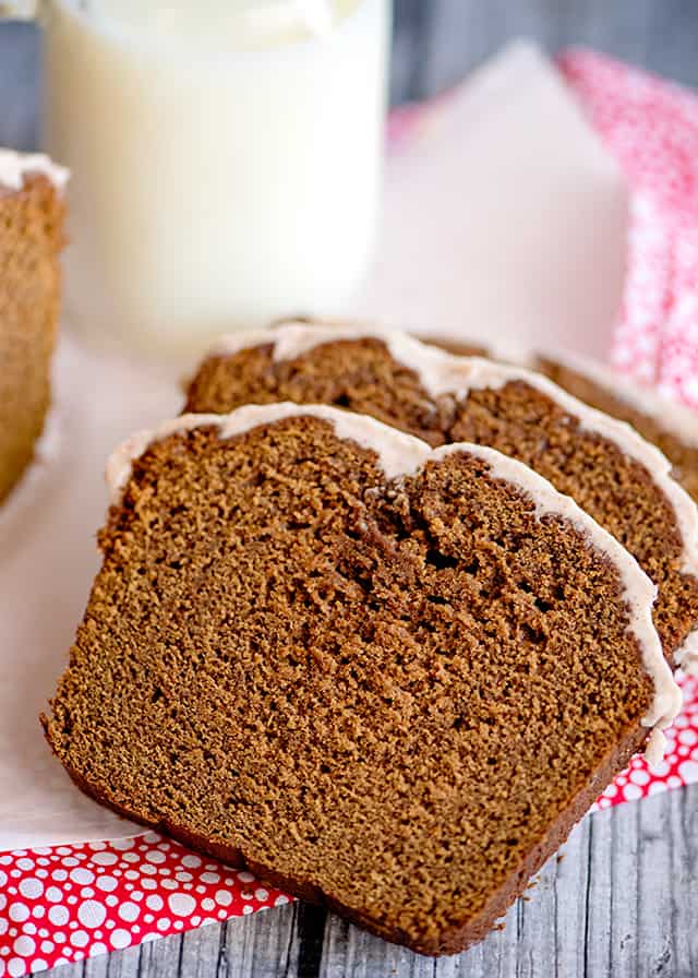 slices of gingerbread loaf on pink fabric with a glass of milk