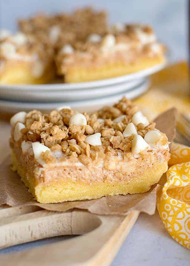 slice of sweet potato cheesecake bars on paper with yellow linen