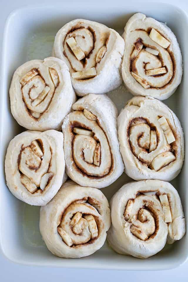 a pan of bananas foster cinnamon rolls rising before being baked