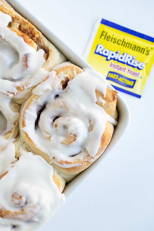 Frosted bananas foster cinnamon rolls in a white baking dish