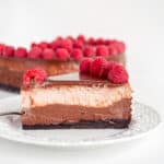 slice of chocolate raspberry cheesecake on a white dessert plate