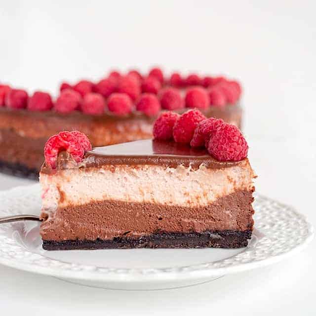 slice of chocolate raspberry cheesecake on a white dessert plate