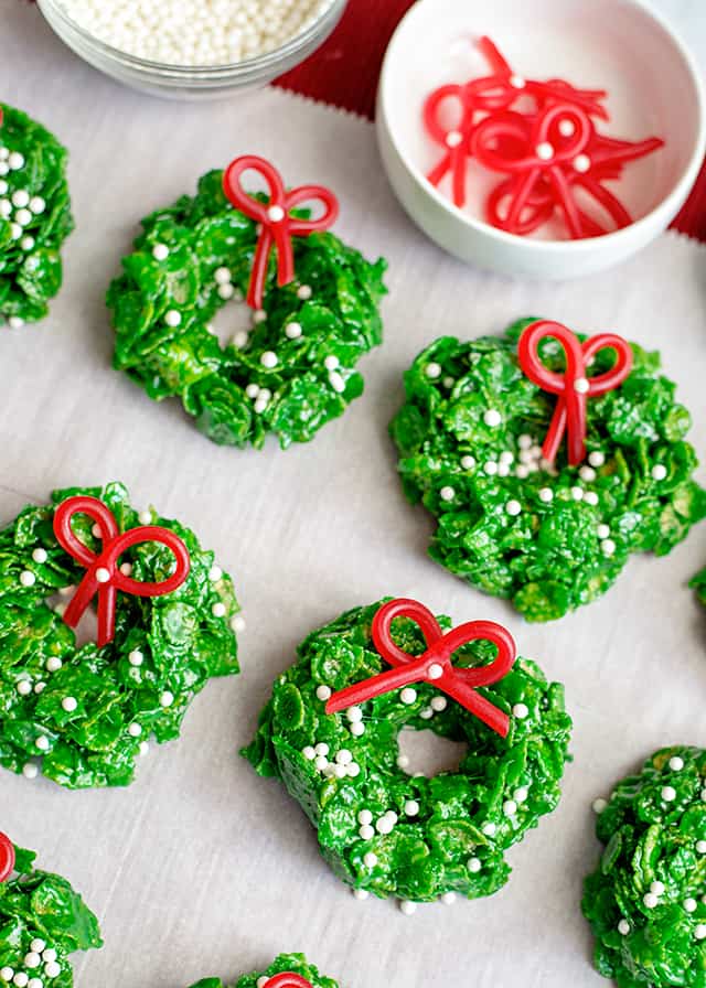 Christmas Wreath Cookies on parchment paper with candy bows in white dish