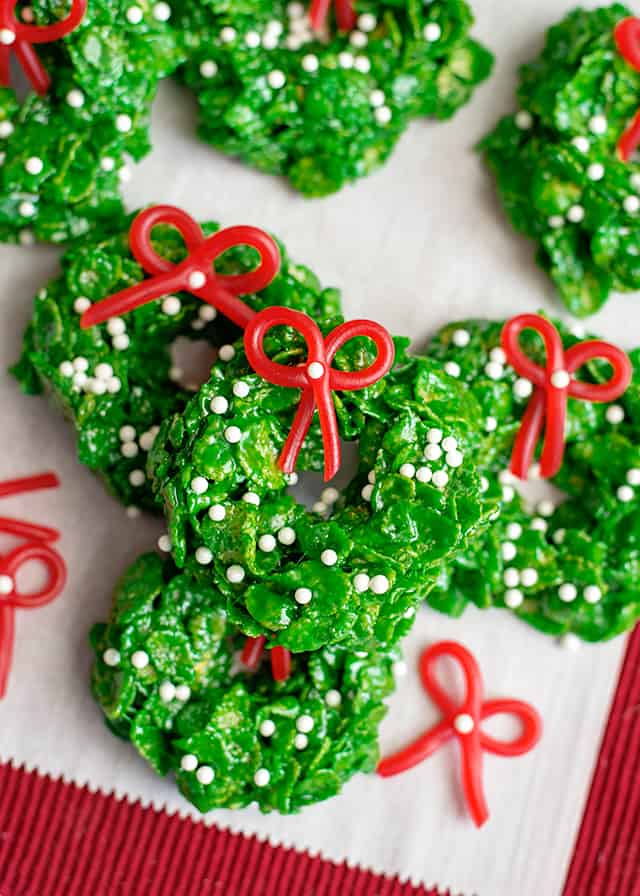 stacked christmas wreath cookies on parchment paper with red fabric underneath