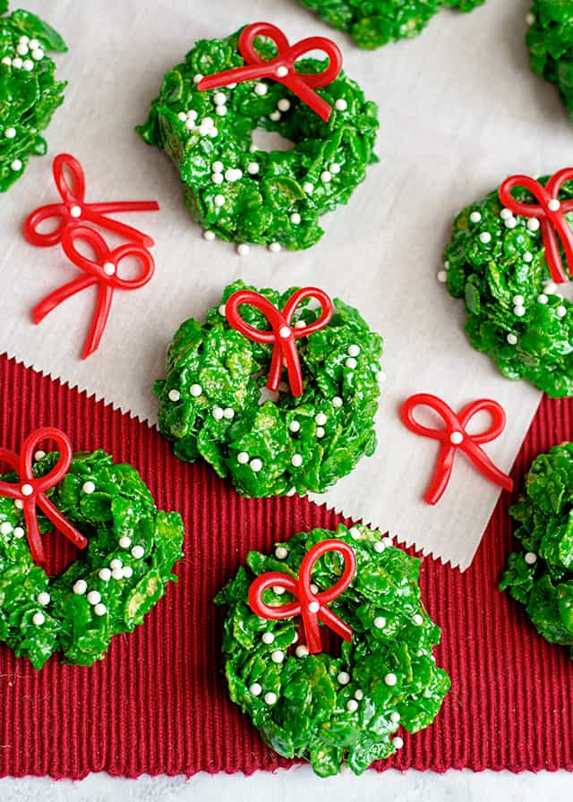 Christmas wreath cookies on parchment paper and red linen with candy bows around them