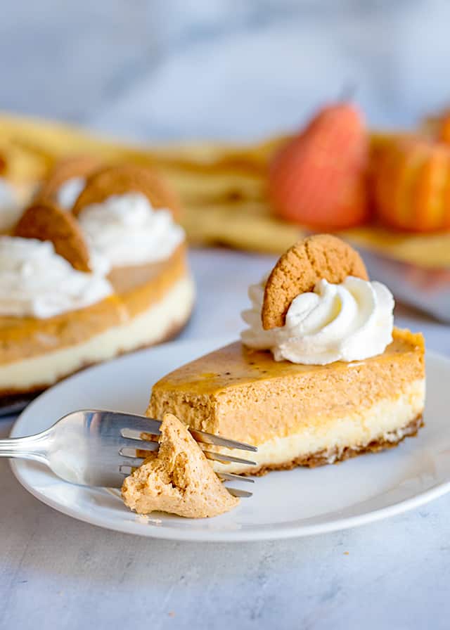 fork full of double layer pumpkin cheesecake on white plate