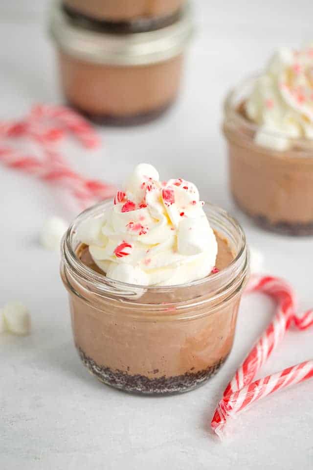 sous vide peppermint hot chocolate cheesecakes with whipped cream and crushed peppermint candy on top