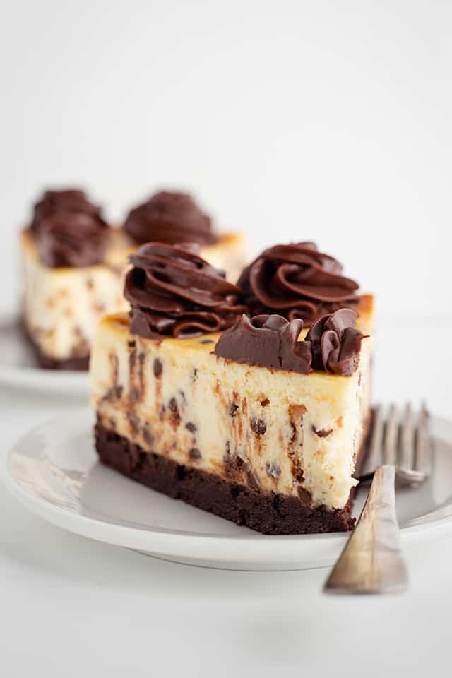 slice of brownie chocolate chip cheesecake on white dessert plate with a fork