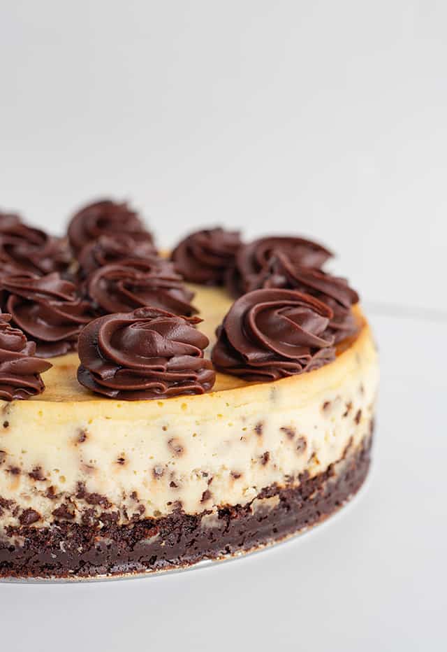 brownie chocolate chip cheesecake with swirls of ganache on a metal plate