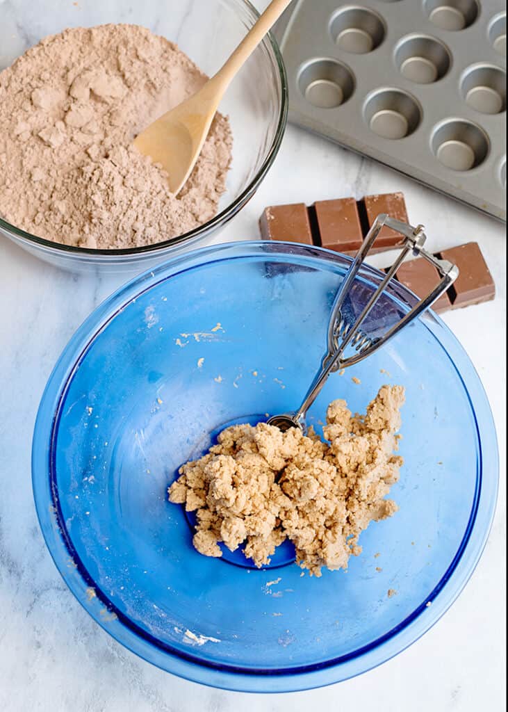 a blue bowl with a peanut butter bal lmixture in it with a brownie mix and almond bark beside it