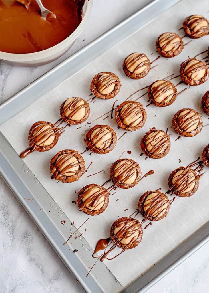 buckeye brownie bites on a parchment paper lined baking sheet and drizzled with almond bark