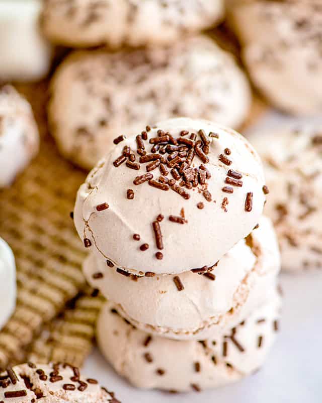 stack of hot cocoa meringue cookies with chocolate sprinkles and burlap background
