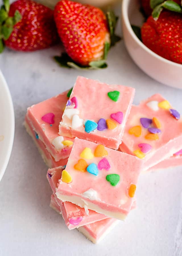 Strawberries and Cream Fudge on white surface with a bowl of strawberries