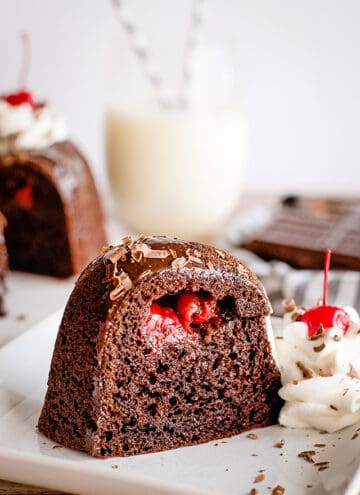 slice of chocolate cherry bundt cake with whipped cream and cherry on white plate