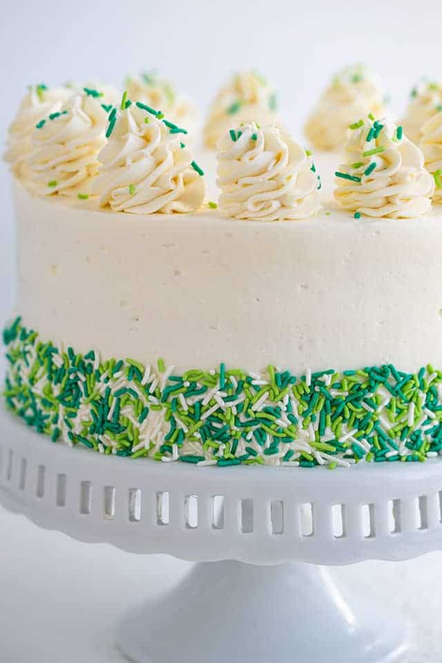 Cheesecake Cake on a white cake plate with green and white sprinkles