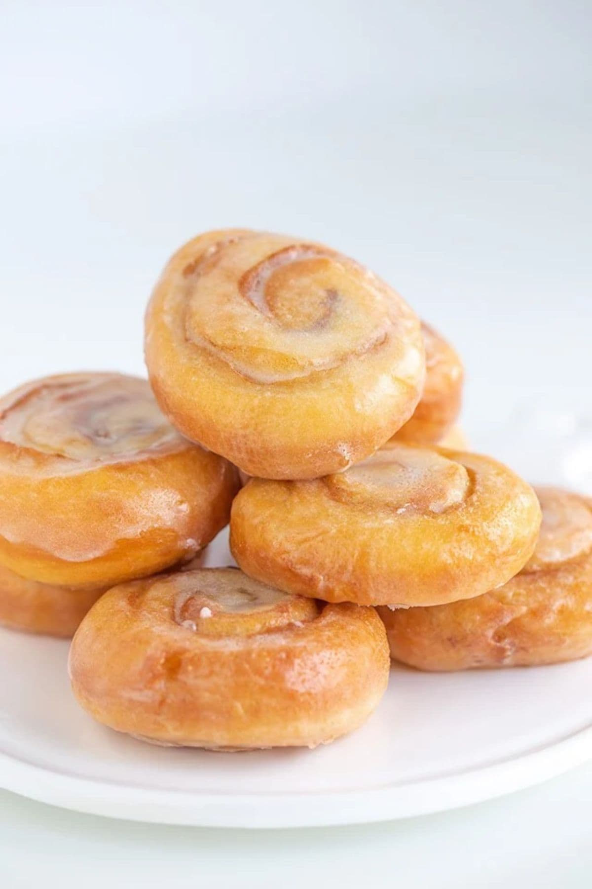 A stack of glazed honey buns on a white plate.
