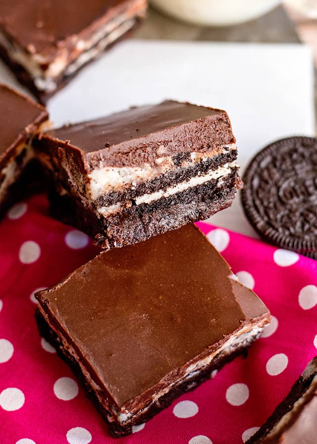 Cookies and cream brownie leaned against another oreo brownie on top of a pink polka dot fabric