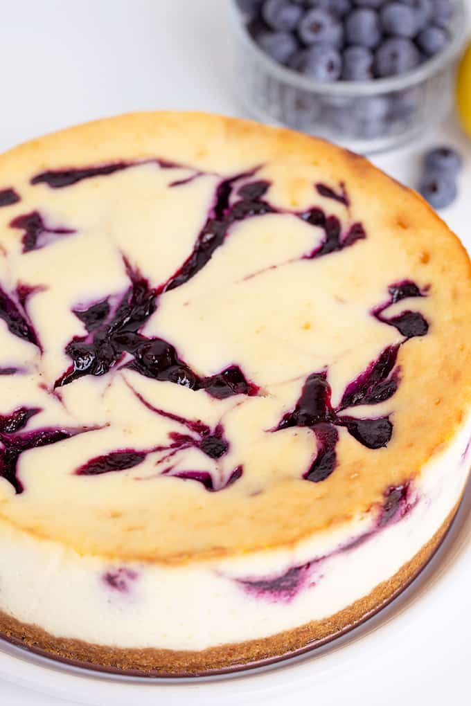whole cheesecake on a white surface showing the top of the cheesecake with the blueberry swirls