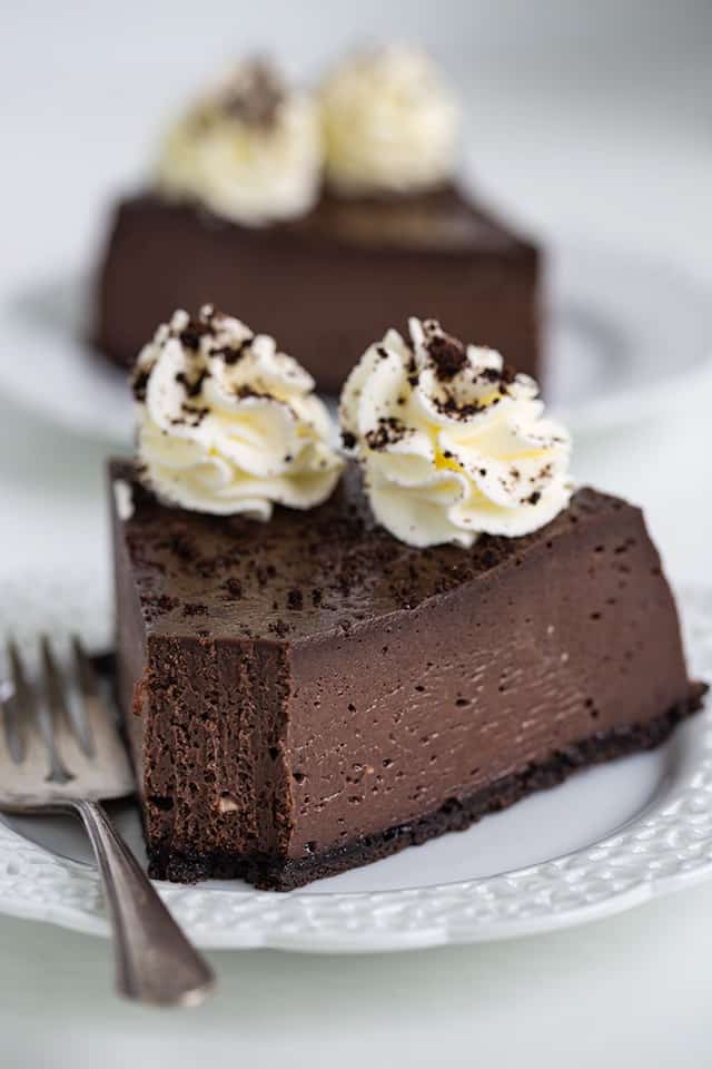 oreo cheesecake with a bite taken out on a white plate with a fork