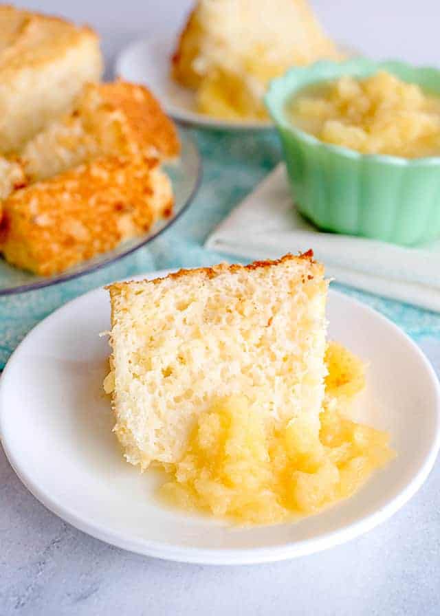 slice of pineapple angel food cake on a white plate with a pineapple sauce